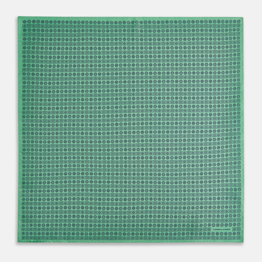 Floral Green Pocket Square in Silk by Turnbull & Asser UK, showcasing navy-blue floral geometric motifs on a bright green background. One corner is neatly folded to display both sides of the silk fabric, with "Turnbull & Asser UK" printed in the lower right corner.