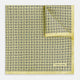 A Floral Yellow Pocket Square in Silk by Turnbull & Asser UK, showcasing a repeating black geometric pattern with subtle floral motifs and the brand logo in one corner. One corner of the fabric is folded over to display the reverse side.
