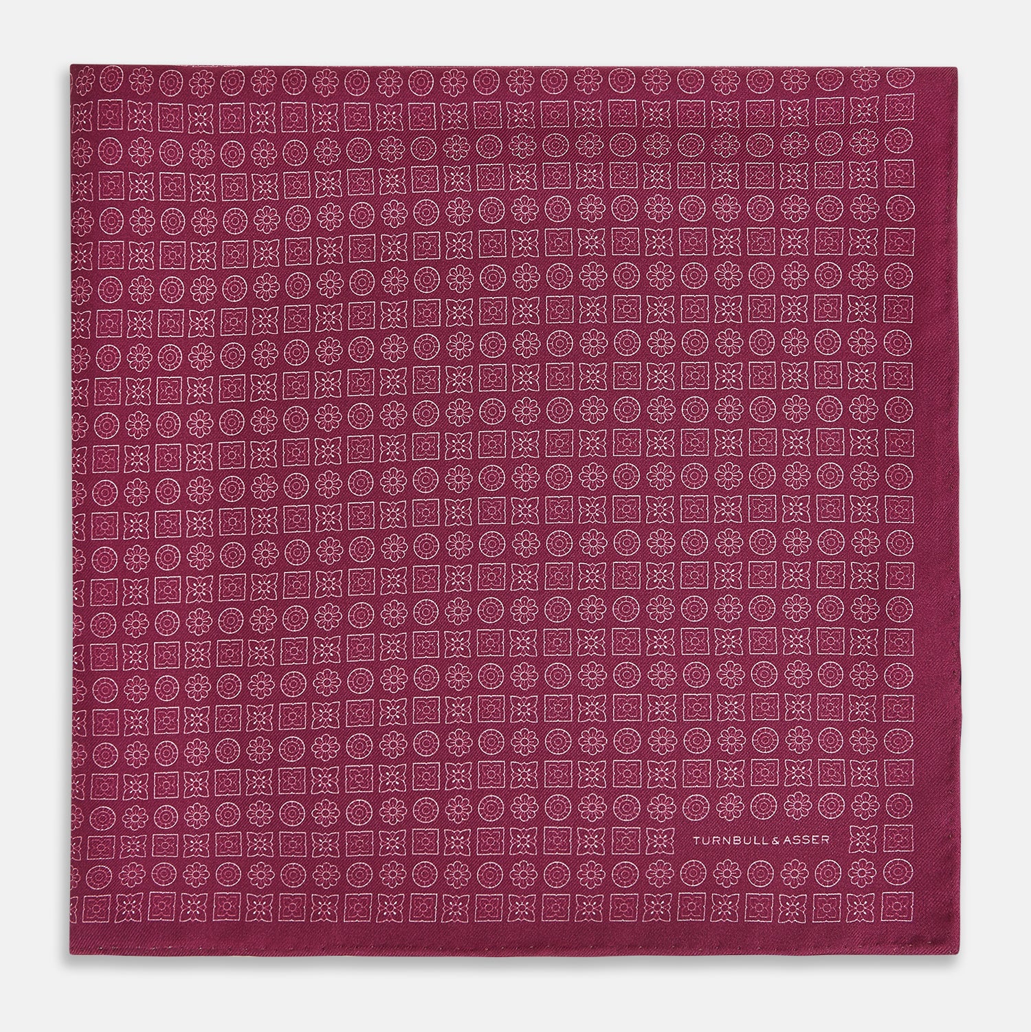 View 3 of product A folded Floral Burgundy Pocket Square in Silk by Turnbull & Asser UK, adorned with pink floral geometric motifs and featuring the Turnbull & Asser logo in the bottom right corner.