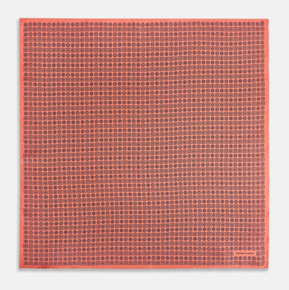 The Floral Orange Pocket Square in Silk by Turnbull & Asser UK features a coral and navy geometric floral pattern with orange accents, neatly folded at the corner. The brand name, Turnbull & Asser UK, is printed in white near the edge.