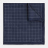 View 1 of product Checked Navy On White Pocket Square in Silk by Turnbull & Asser UK, featuring a navy blue geometric pattern with a white dotted grid and a solid border. The pocket square is shown with one corner folded over to display the “TURNBULL & ASSER” label in white text.