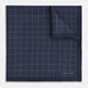 Checked Navy On White Pocket Square in Silk by Turnbull & Asser UK, featuring a navy blue geometric pattern with a white dotted grid and a solid border. The pocket square is shown with one corner folded over to display the “TURNBULL & ASSER” label in white text.