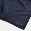 View 2 of product Checked Navy On White Pocket Square in Silk by Turnbull & Asser UK, featuring a navy blue geometric pattern with a white dotted grid and a solid border. The pocket square is shown with one corner folded over to display the “TURNBULL & ASSER” label in white text.