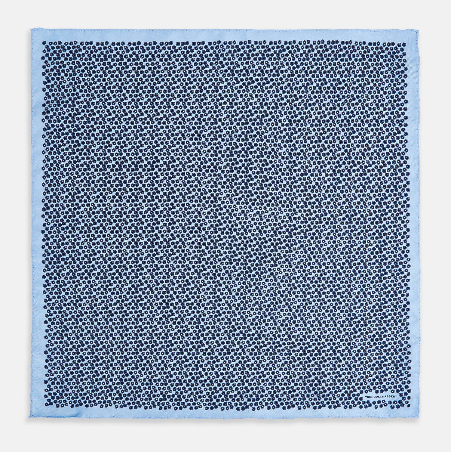 View 4 of product A light blue double-sided pocket square made of silk, featuring a dense pattern of small, dark blue floral motifs. One corner is folded over to reveal the Turnbull & Asser UK brand name printed in blue.