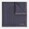 View 1 of product A folded Floral Purple Pocket Square in Silk by Turnbull & Asser UK, featuring a double-sided design with a pattern of small, dark blue circles and the brand’s logo printed in one corner.
