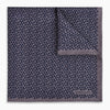 View 4 of product A folded Floral Purple Pocket Square in Silk by Turnbull & Asser UK, featuring a double-sided design with a pattern of small, dark blue circles and the brand’s logo printed in one corner.