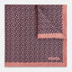 A folded Floral Pink Pocket Square in Silk by Turnbull & Asser UK, adorned with a pattern of small navy blue circles and the brand name printed in one corner, features a refined double-sided design for added versatility.