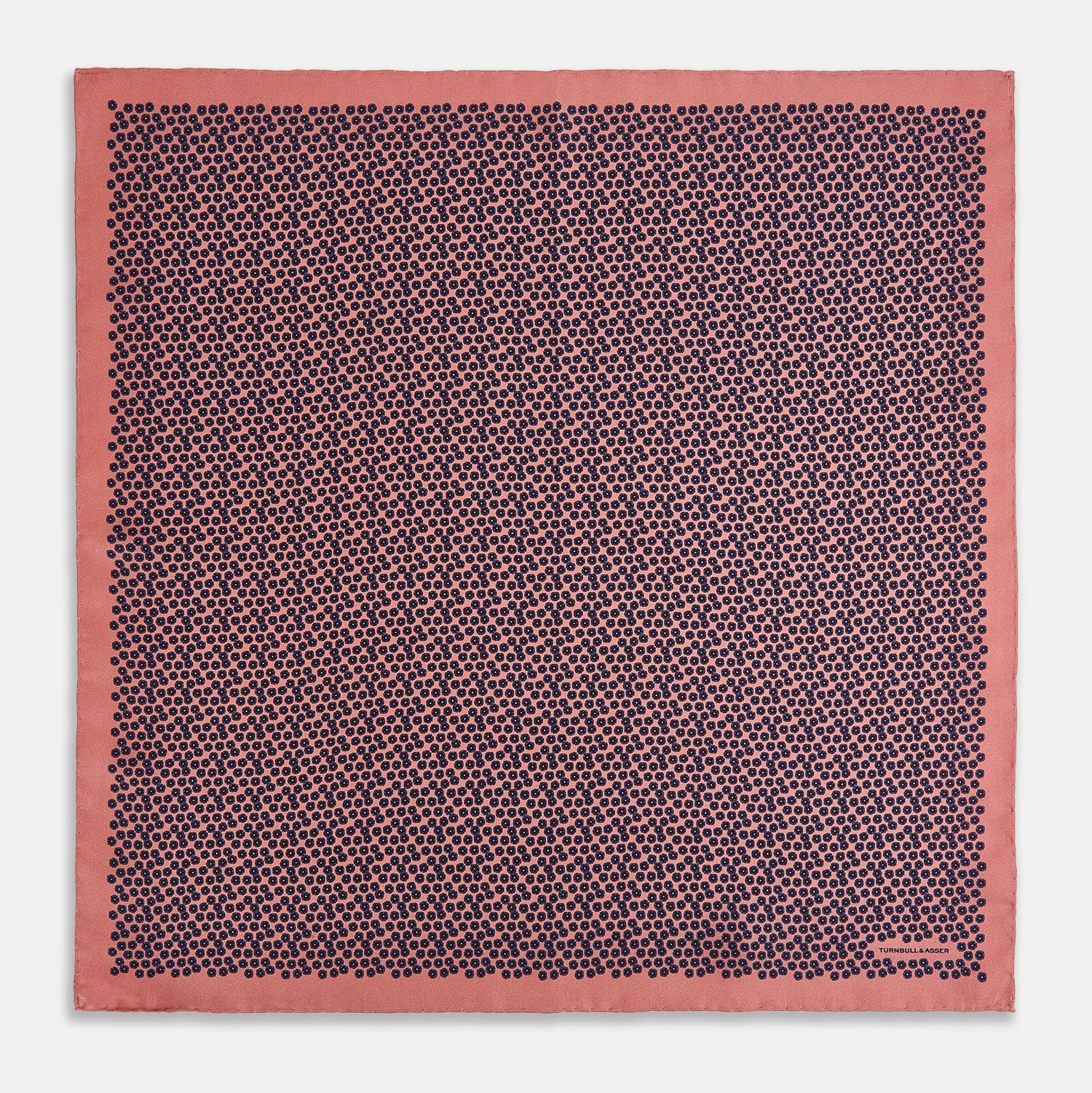 View 4 of product A folded Floral Pink Pocket Square in Silk by Turnbull & Asser UK, adorned with a pattern of small navy blue circles and the brand name printed in one corner, features a refined double-sided design for added versatility.