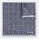 A folded, square Turnbull & Asser UK Geometric Grey Pocket Square in Silk featuring a geometric black and white concentric squares pattern accented with subtle navy lines, finished with a small Turnbull & Asser label in one corner.