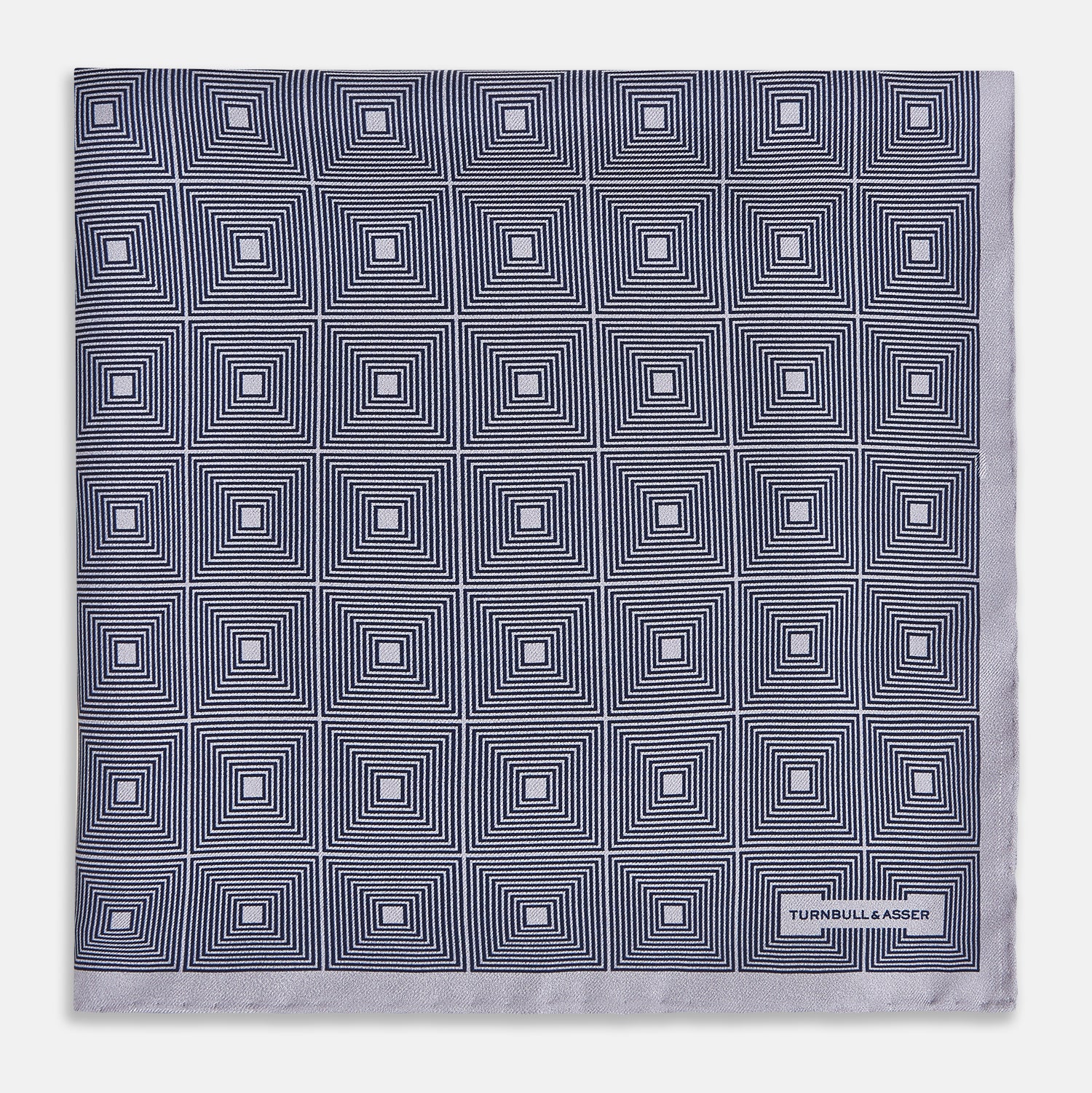 View 3 of product A folded, square Turnbull & Asser UK Geometric Grey Pocket Square in Silk featuring a geometric black and white concentric squares pattern accented with subtle navy lines, finished with a small Turnbull & Asser label in one corner.