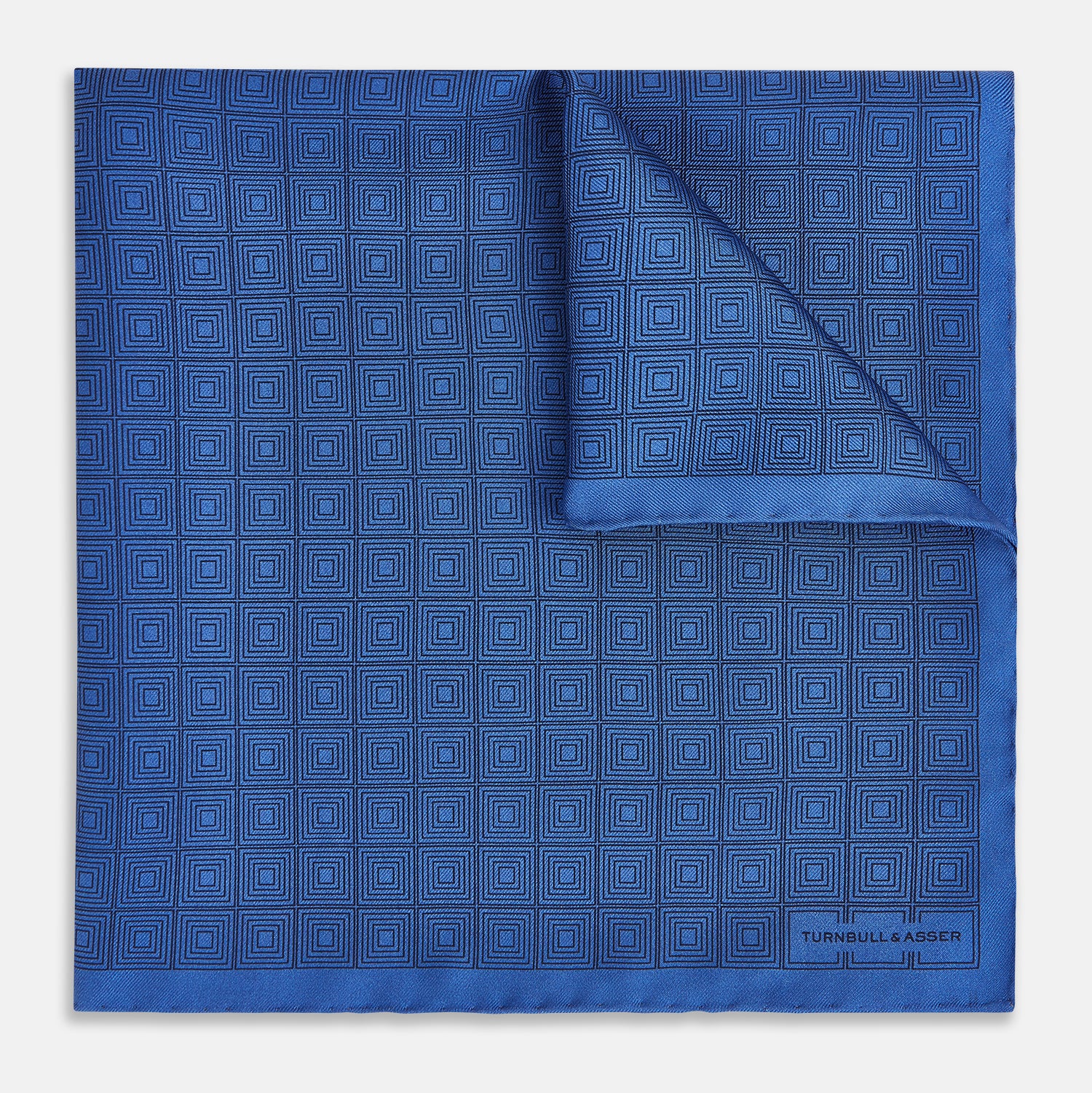View 1 of product The Geometric Blue Pocket Square in Silk by Turnbull & Asser UK features a vibrant blue design adorned with small, outlined squares arranged in a grid of sharp navy lines. One corner is neatly folded to reveal the reverse side, with "Turnbull & Asser" printed at the bottom right.