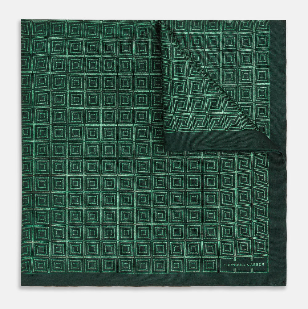 The Geometric Green Pocket Square in Silk by Turnbull & Asser UK features a sophisticated forest green hue with a geometric pattern of concentric squares and a visible Turnbull & Asser label in the corner.