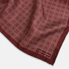 View 2 of product The Geometric Burgundy Pocket Square in Silk by Turnbull & Asser UK features a refined pattern of small, repeating white squares on a rich burgundy background—an ideal accessory for introducing sophistication to any outfit. One corner is artfully folded over to showcase the reverse side of this elegant geometric design, and the "Turnbull & Asser" label appears in the bottom right corner.