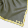 View 2 of product A folded yellow silk pocket square with a subtle polka dot pattern and yellow edges, perfect for formal tailoring. The Turnbull & Asser UK label is visible in one corner.