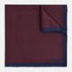 A Polka dot Burgundy Pocket Square in Silk by Turnbull & Asser UK, featuring a subtle micro motif and a solid navy border, partially folded at the top right corner.