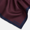 View 2 of product A Polka dot Burgundy Pocket Square in Silk by Turnbull & Asser UK, featuring a subtle micro motif and a solid navy border, partially folded at the top right corner.