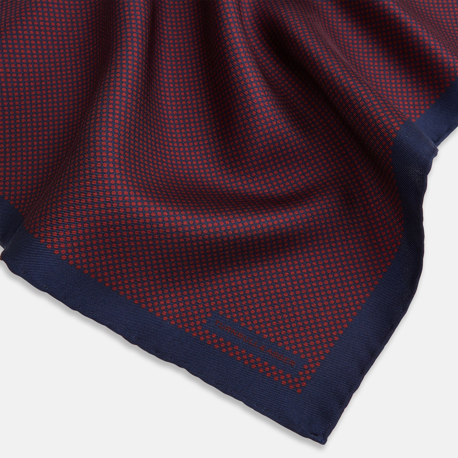 View 2 of product A Polka dot Burgundy Pocket Square in Silk by Turnbull & Asser UK, featuring a subtle micro motif and a solid navy border, partially folded at the top right corner.