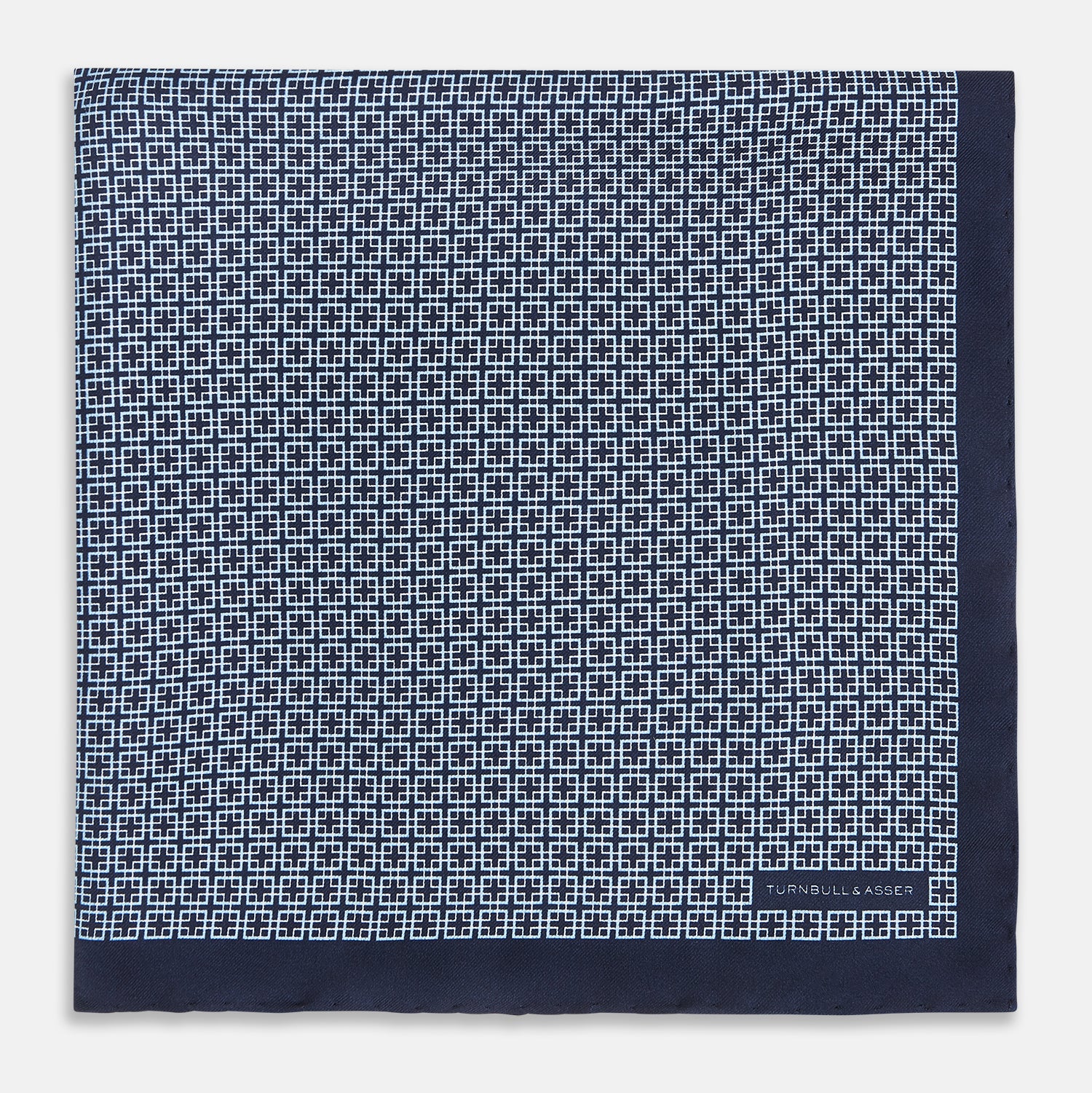 View 3 of product Introducing the Geometric Navy Pocket Square in Silk by Turnbull & Asser UK. This sophisticated accessory showcases a small, repeating geometric pattern in light blue and white on a rich navy background. The pocket square features a solid navy border, while the folded corner reveals the underside adorned with the Turnbull & Asser logo—an elegant finishing touch for any formal ensemble.