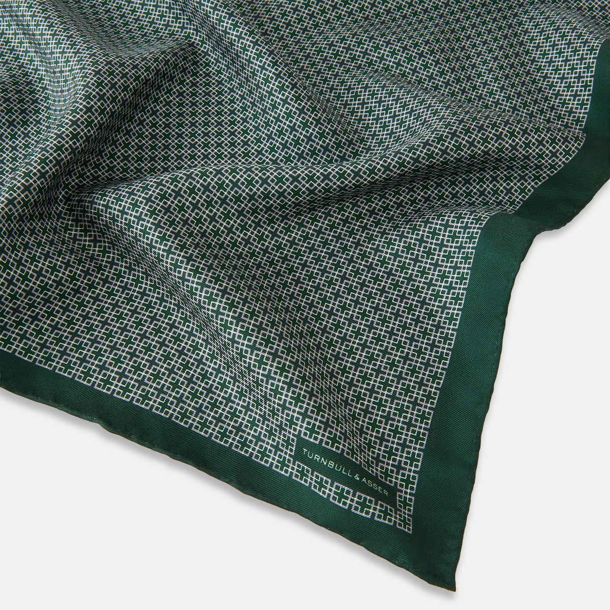 View 2 of product Turnbull & Asser UK Geometric Green Forest Green Pocket Square in Silk featuring a white geometric motif and a solid green border.