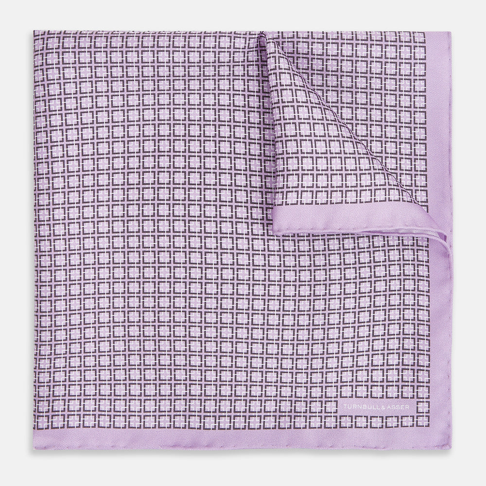 Crafted by Turnbull & Asser UK, the Geometric Lilac Pocket Square in Silk features an elegant square pattern in lilac hues, accented by a solid lavender border. When folded, it tastefully displays a glimpse of the sophisticated patterned underside.