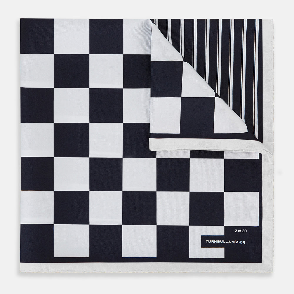 A square silk pocket square featuring a navy-on-white chequered pattern, labeled Turnbull & Asser UK with 2 of 20 in the bottom right corner—part of the limited edition Chequered Navy on White Frame Pocket Square from the Driver’s Capsule Collection.