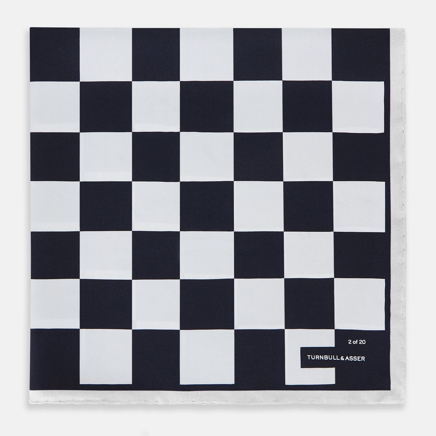 View 1 of product A square silk pocket square featuring a navy-on-white chequered pattern, labeled Turnbull & Asser UK with 2 of 20 in the bottom right corner—part of the limited edition Chequered Navy on White Frame Pocket Square from the Driver’s Capsule Collection.