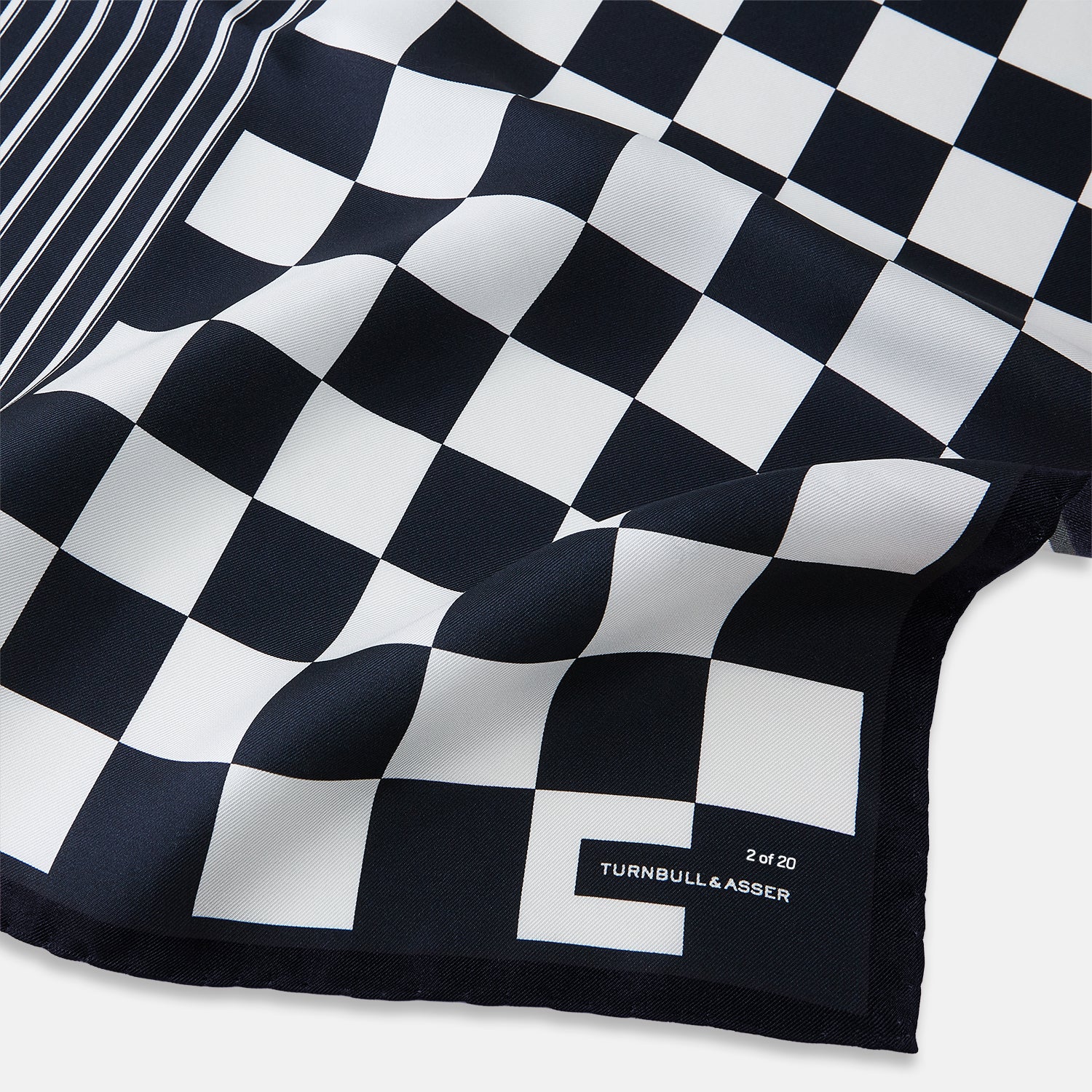 View 2 of product A chequered navy on navy frame silk pocket square from Turnbull & Asser UK, this piece is a limited edition from the Driver’s Capsule Collection, featuring “Turnbull & Asser” and “2 of 20” printed in one corner.