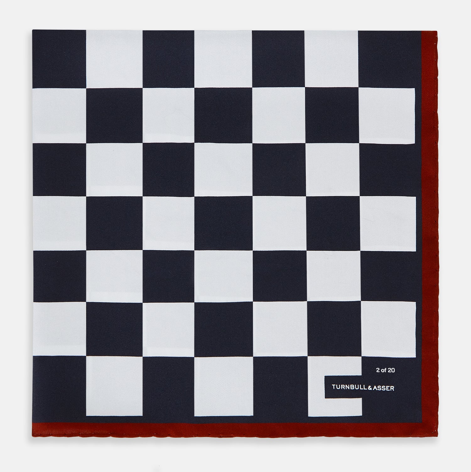 View 1 of product Introducing the Chequered Navy on Red Frame Pocket Square in Silk from Turnbull & Asser UK. This limited edition accessory, part of the Driver’s Capsule Collection, features a bold navy and white checkerboard pattern bordered by deep red silk. The bottom right corner is subtly detailed with white text reading “Turnbull & Asser” and “2 of 20.”.