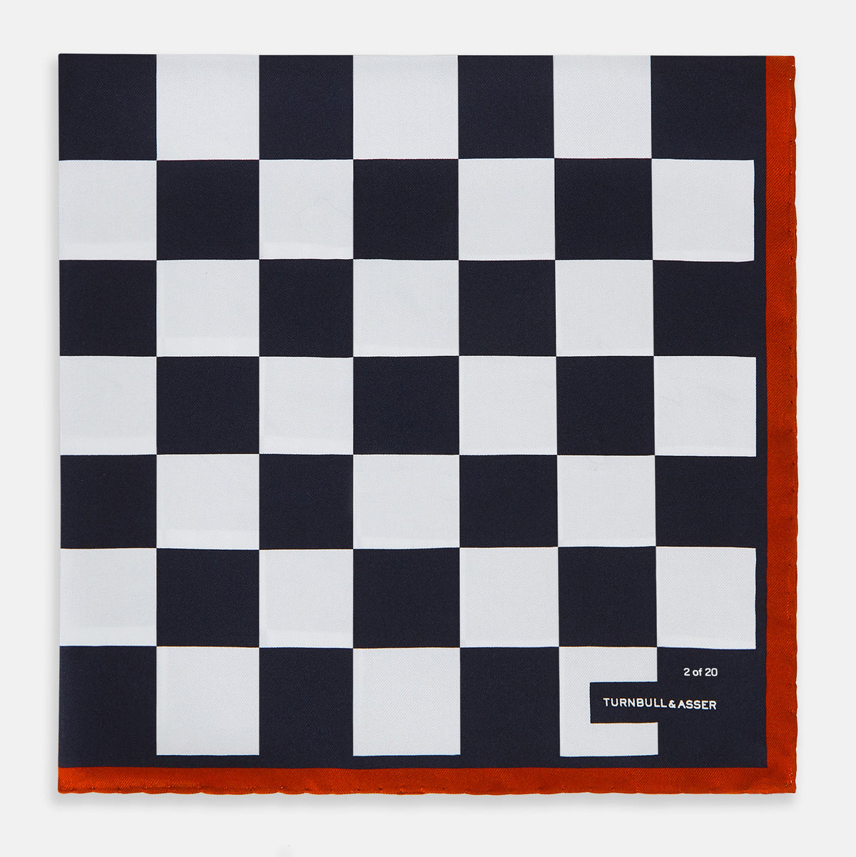 View 3 of product A limited edition silk pocket square from Turnbull & Asser UK, featuring a striking navy chequered pattern framed by a bold red border and finished with the text TURNBULL & ASSER in one corner. Part of the exclusive Driver’s Capsule Collection.