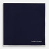 View 3 of product The Navy Piped Silk Pocket Square by Turnbull & Asser features white-stitched edges and subtle brand embroidery, ideal for enhancing formal looks. Shown neatly folded on a plain white background.