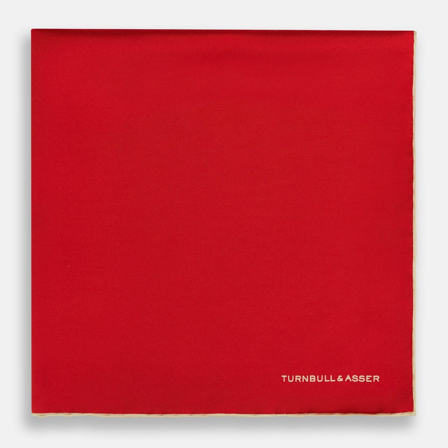 View 3 of product The Turnbull & Asser RED AND GOLD PIPED SILK POCKET SQUARE is a vibrant red silk accessory with gold edging and the brand’s logo in white on the bottom right—ideal for elevating formal looks.
