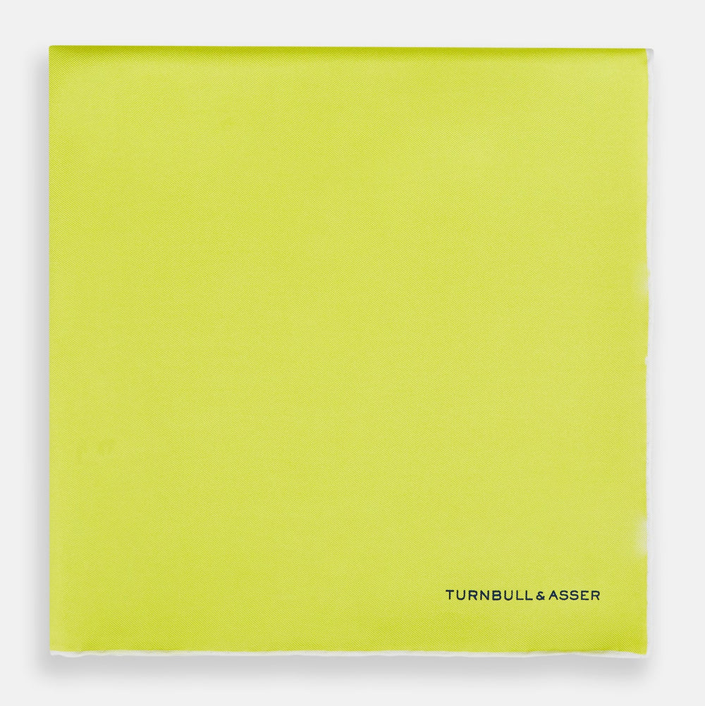 The Canary Yellow Piped Silk Pocket Square by Turnbull & Asser features white edges and black branding in the bottom right corner, making it a perfect accessory for formal attire. Shown on a plain white background.