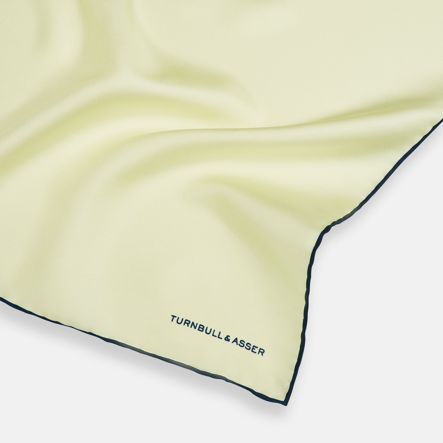View 2 of product The Turnbull & Asser GOLD AND NAVY BLUE PIPED SILK POCKET SQUARE features navy piping and an embroidered logo—a refined accessory to elevate any formal look.