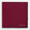 View 3 of product The Mauve Piped Silk Pocket Square by Turnbull & Asser features a dark blue edge and white embroidered logo in the lower right corner, making it ideal for formal occasions. Displayed on a plain white background.