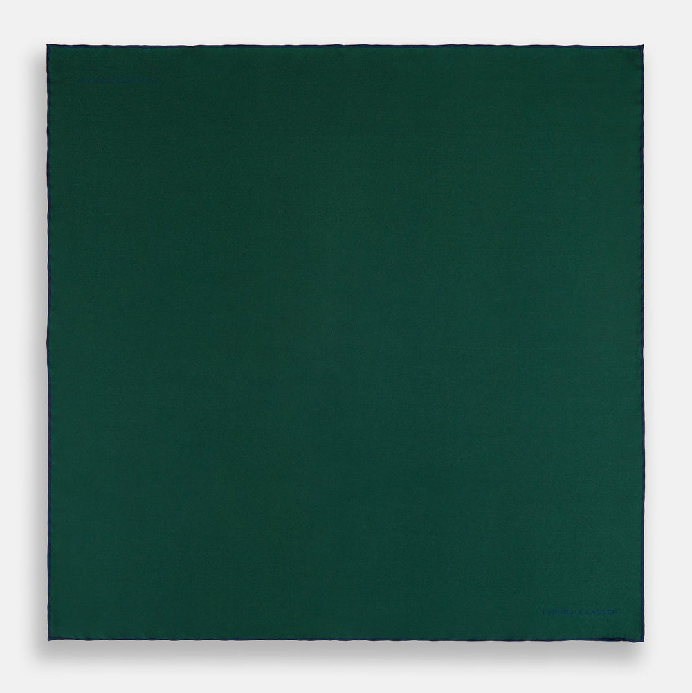The Turnbull & Asser Petrol Green Piped Silk Pocket Square features a visible stitched edge and a discreet blue logo on the turned-down corner, adding an elegant accent to formal attire.