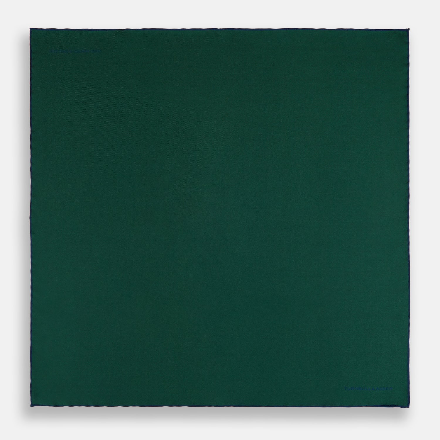 View 4 of product The Turnbull & Asser Petrol Green Piped Silk Pocket Square features a visible stitched edge and a discreet blue logo on the turned-down corner, adding an elegant accent to formal attire.