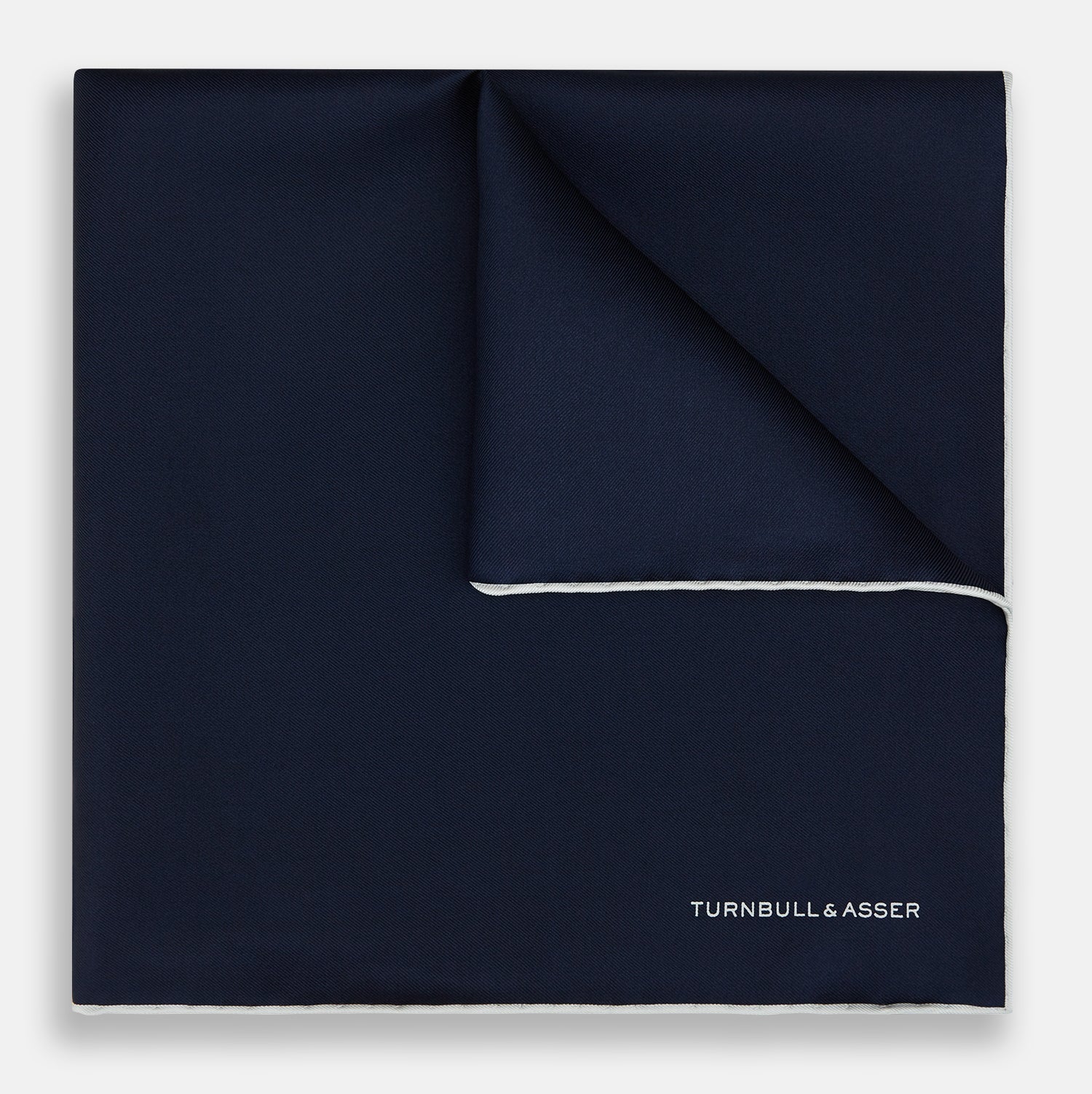 View 1 of product The Midnight Blue Piped Silk Pocket Square from Turnbull & Asser features crisp white trim and subtle branding, making it the ideal accessory to elevate your formal look.