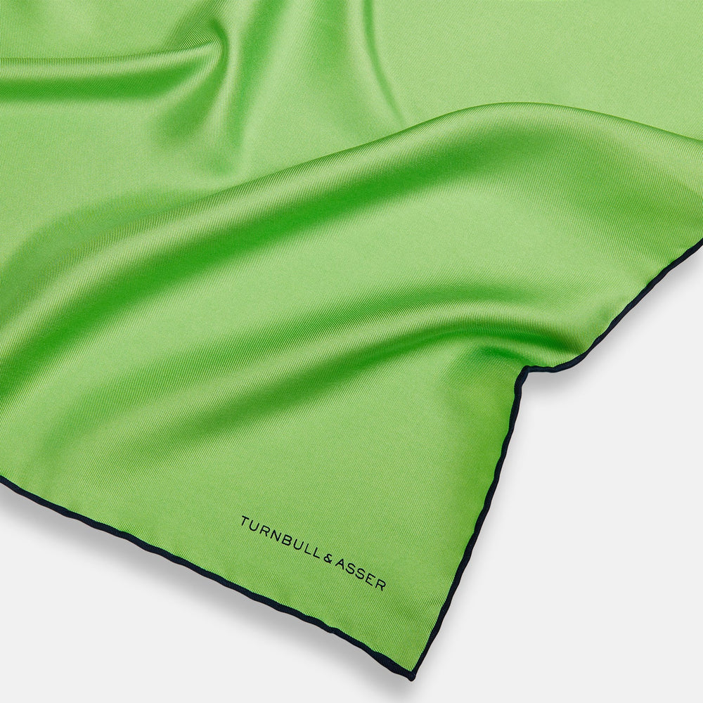 A neatly folded Turnbull & Asser LIGHT GREEN AND BLACK PIPED SILK POCKET SQUARE—ideal for elevating formal attire.