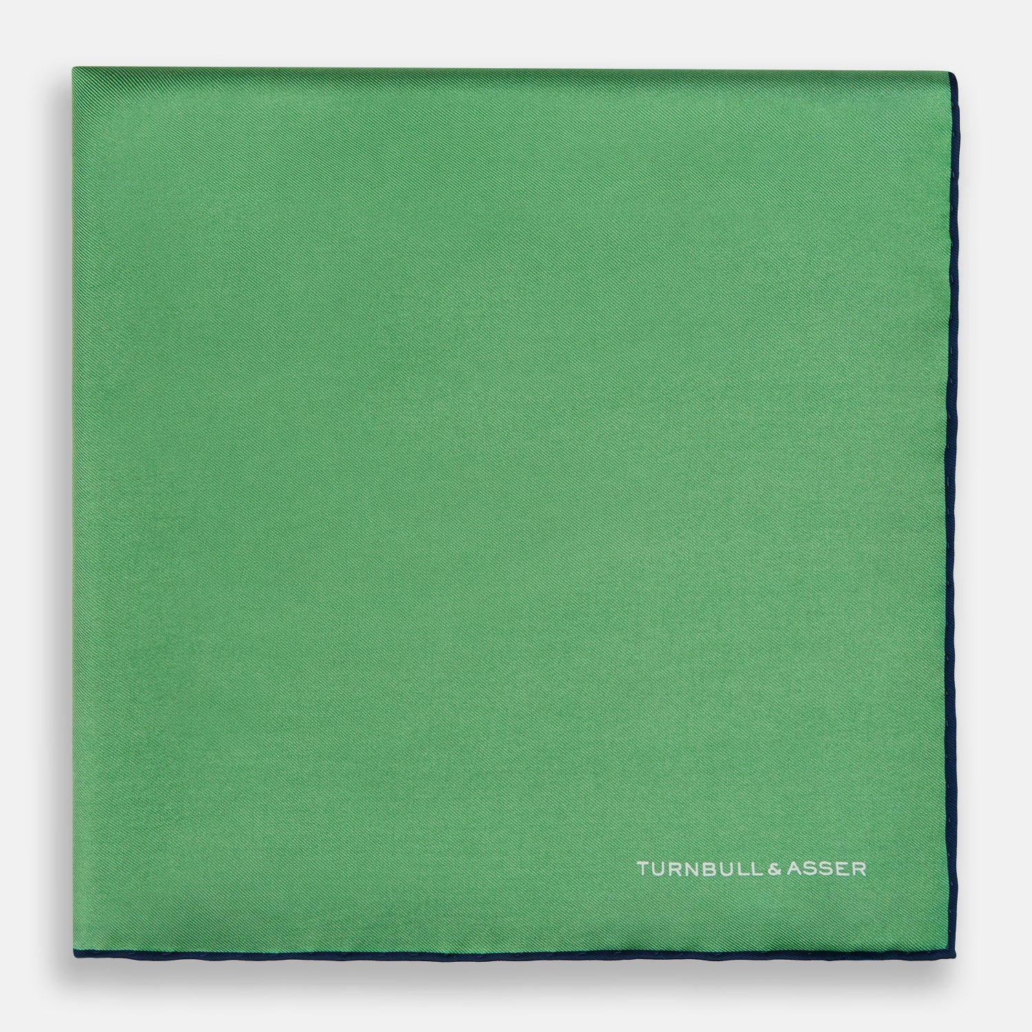 View 3 of product The Fern Green Piped Silk Pocket Square by Turnbull & Asser features a dark blue edge and white embroidered branding at the corner—an elegant accessory for formal wear.