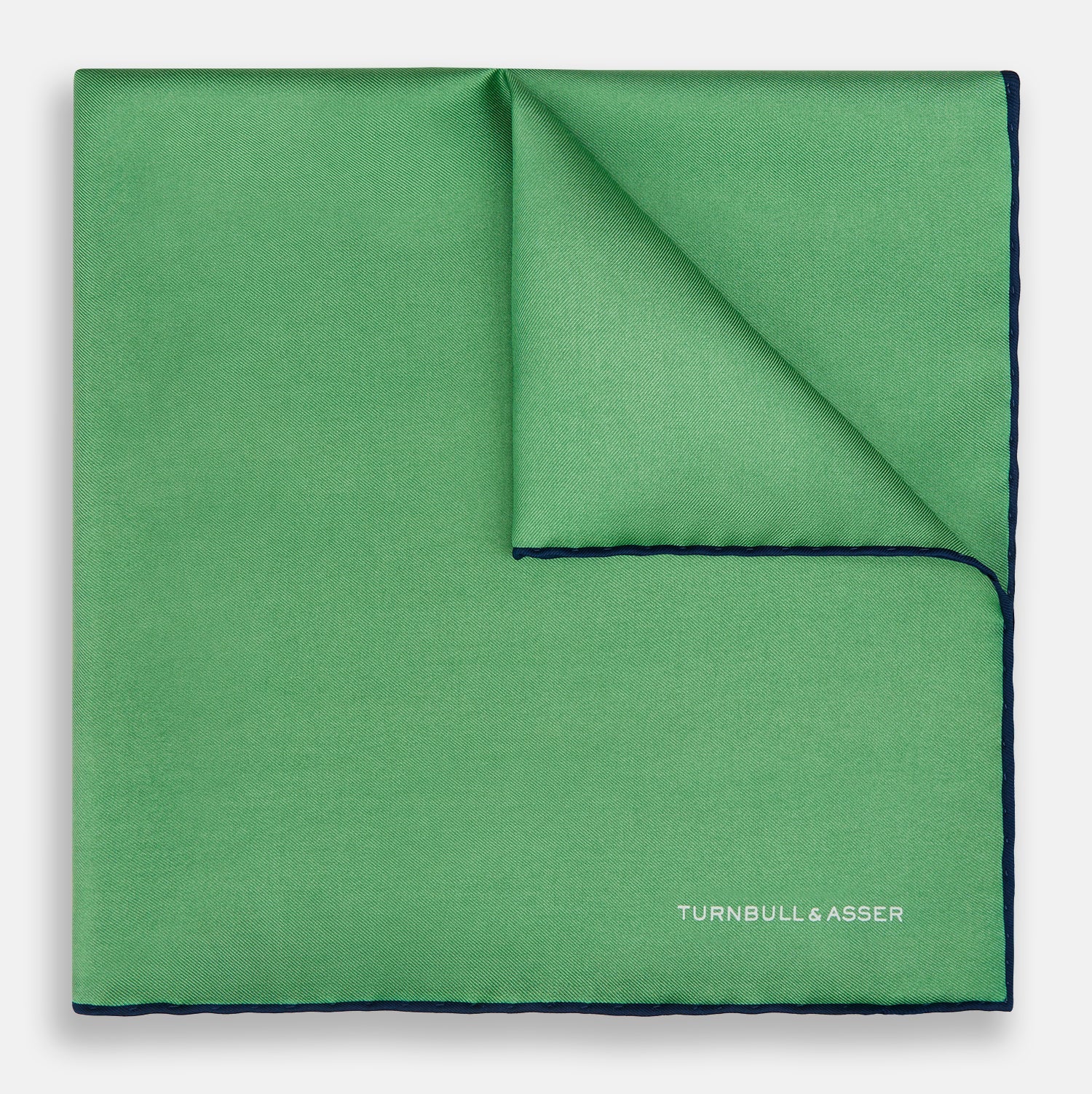 View 1 of product The Fern Green Piped Silk Pocket Square by Turnbull & Asser features a dark blue edge and white embroidered branding at the corner—an elegant accessory for formal wear.
