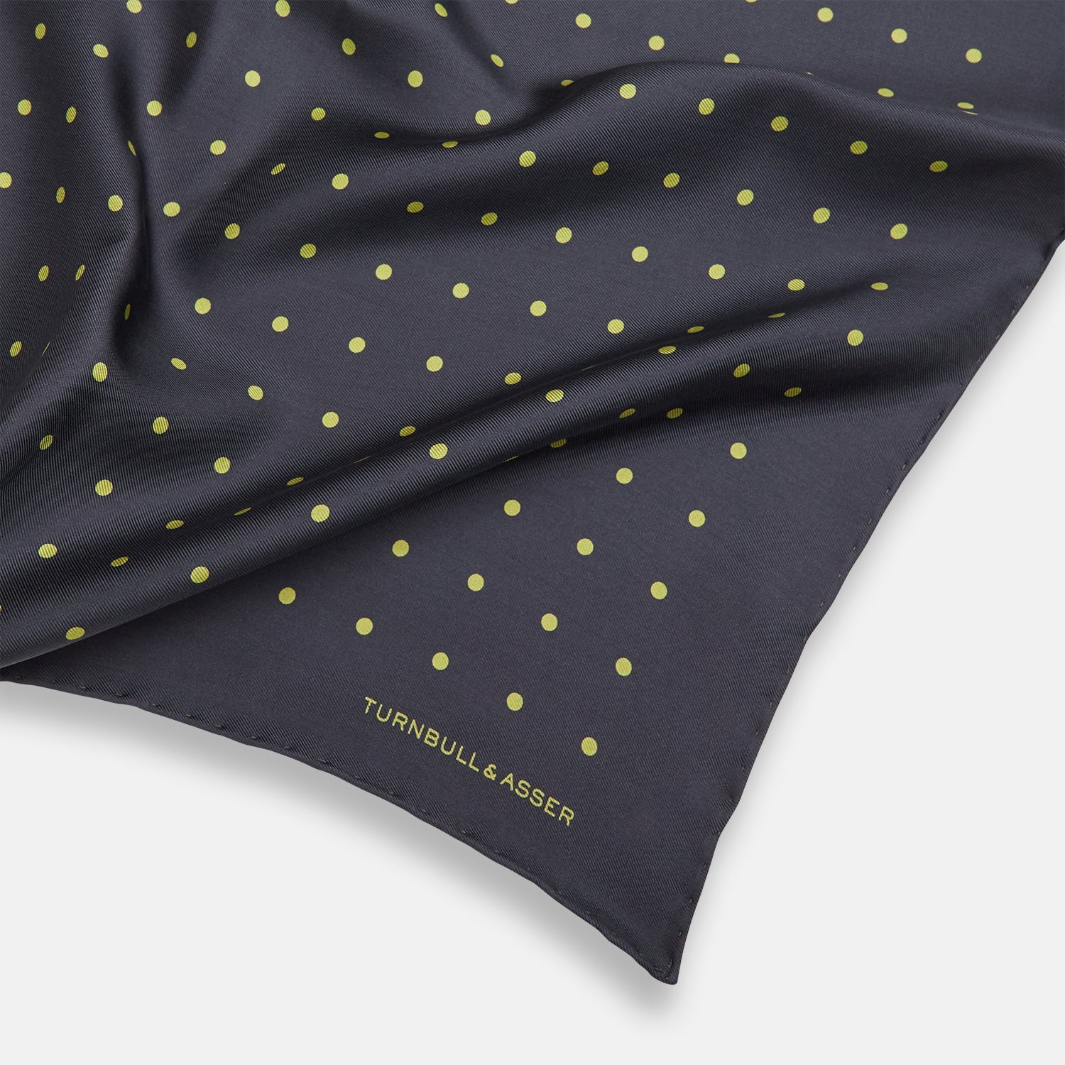 View 2 of product A grey and lime spot silk pocket square by Turnbull & Asser, featuring evenly spaced dots and the brand's logo in one corner—perfect for adding a stylish touch to formal attire.