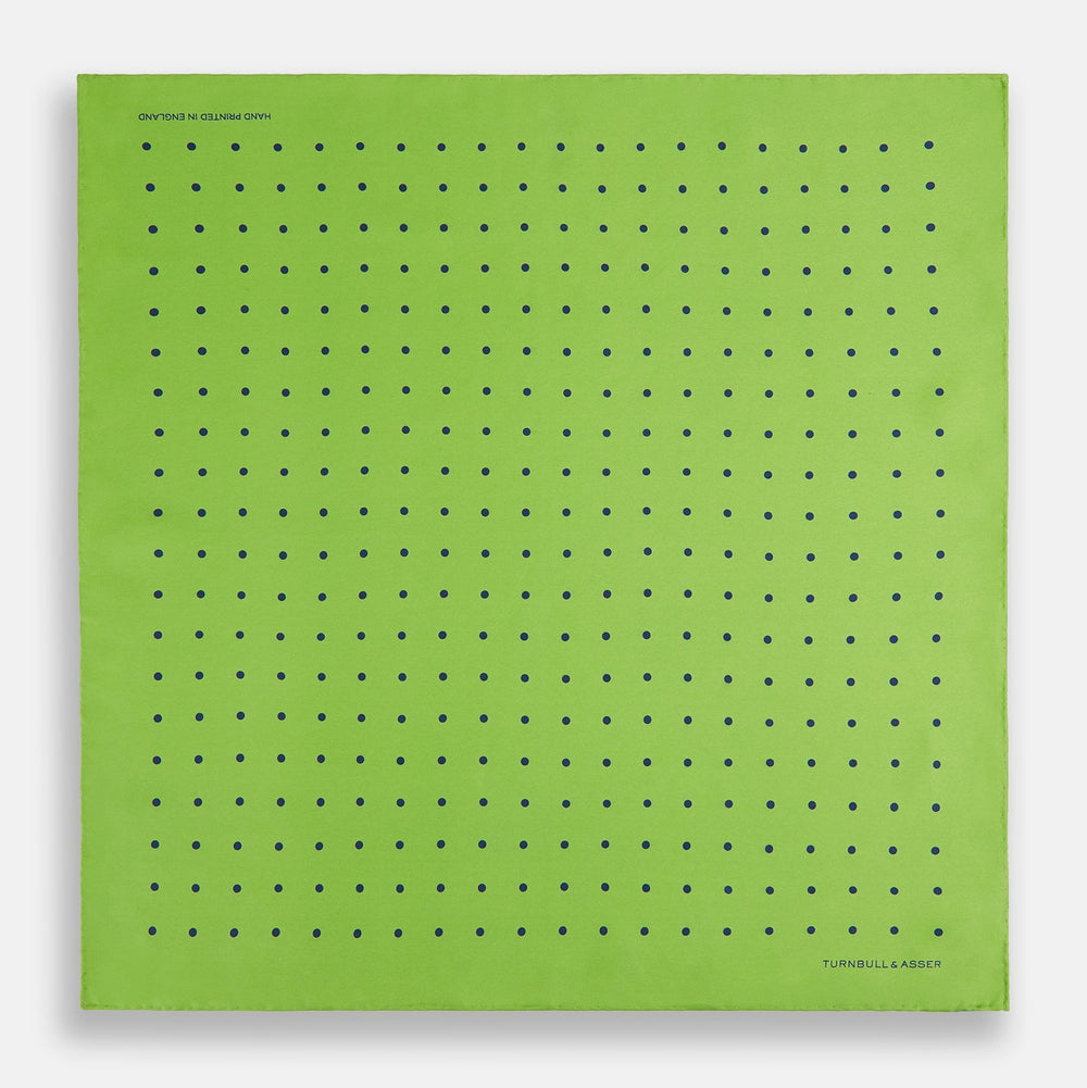 The Turnbull & Asser Lime Green and Blue Spot Silk Pocket Square features evenly spaced blue dots and the brand’s text in the bottom right corner. One corner is folded to reveal the reverse, making it ideal for formal occasions.