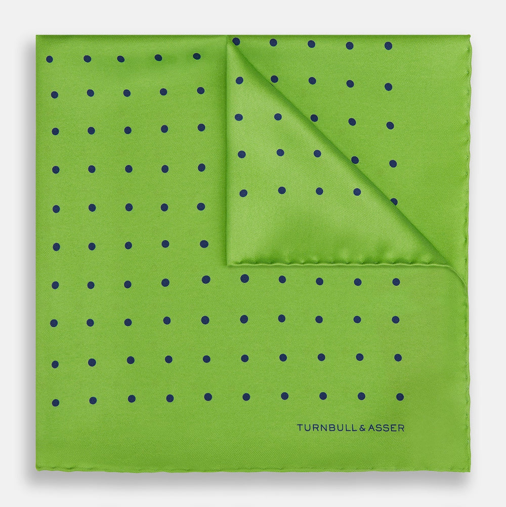 The Turnbull & Asser Lime Green and Blue Spot Silk Pocket Square features evenly spaced blue dots and the brand’s text in the bottom right corner. One corner is folded to reveal the reverse, making it ideal for formal occasions.