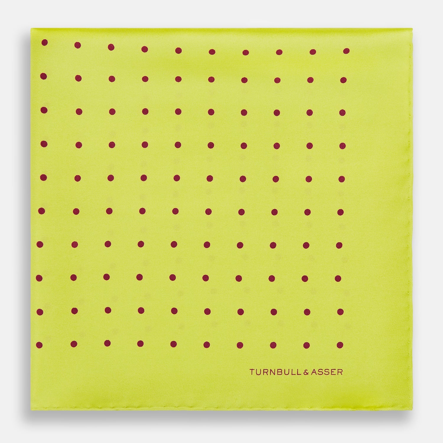 View 3 of product The Turnbull & Asser Chartreuse and Mauve Spot Silk Pocket Square features evenly spaced mauve dots and a branded corner—an ideal accessory to enhance your formal look.