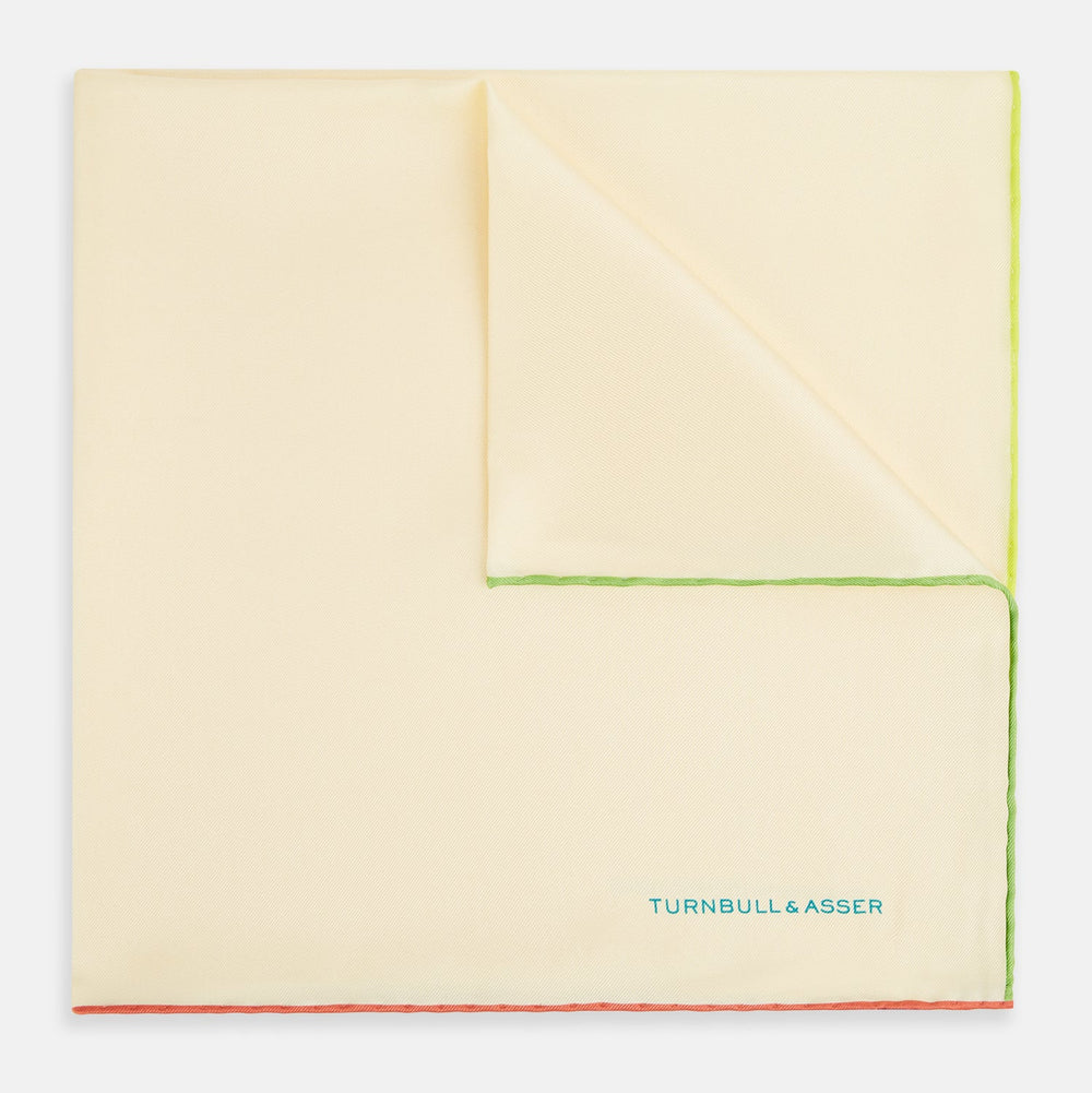 The Turnbull & Asser Ecru and Multicoloured Piped Silk Pocket Square features green and orange piping, blue "TURNBULL & ASSER" embroidery in the lower right, and a folded corner—a refined accessory for formal wear.