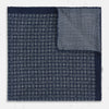 View 3 of product The Rosette Navy Pocket Square in Silk by Turnbull & Asser UK is a square, navy blue accessory featuring a small geometric pattern. Shown laid flat with one corner folded, it reveals a contrasting, finer motif on the reverse side. This elegant double-sided design offers versatile styling options for any occasion.