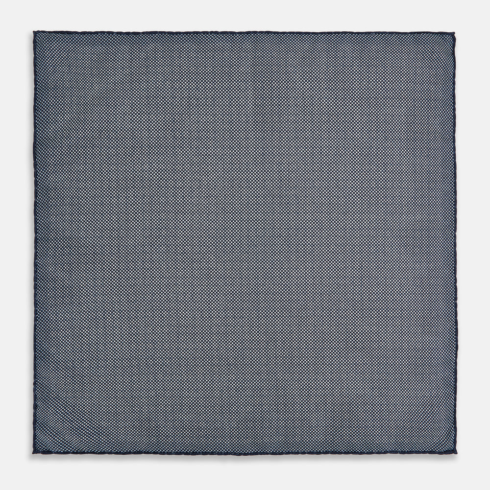 The Rosette Navy Pocket Square in Silk by Turnbull & Asser UK is a square, navy blue accessory featuring a small geometric pattern. Shown laid flat with one corner folded, it reveals a contrasting, finer motif on the reverse side. This elegant double-sided design offers versatile styling options for any occasion.