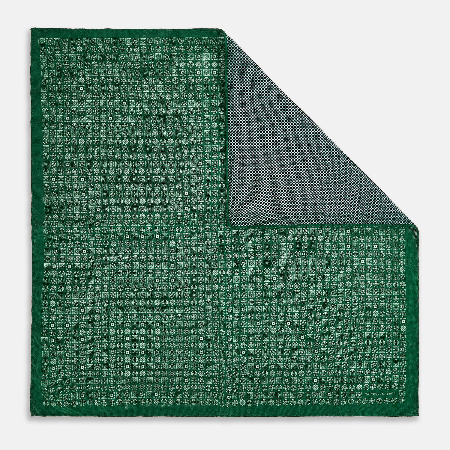 View 1 of product The Rosette Green Pocket Square in Silk by Turnbull & Asser UK features a small geometric medallion pattern and is shown folded to display a contrasting fine black-and-white design on the reverse side.