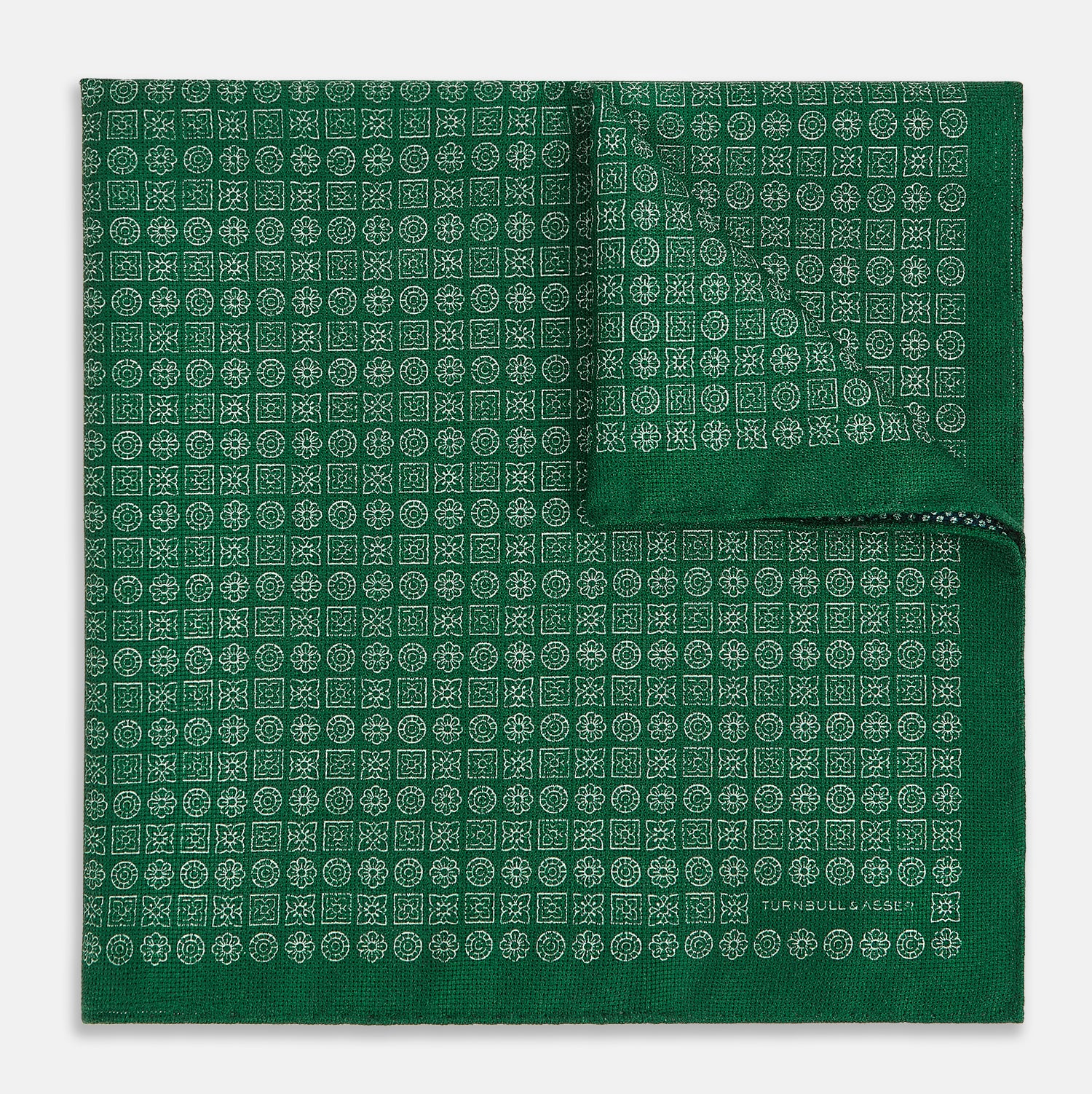 View 2 of product The Rosette Green Pocket Square in Silk by Turnbull & Asser UK features a small geometric medallion pattern and is shown folded to display a contrasting fine black-and-white design on the reverse side.