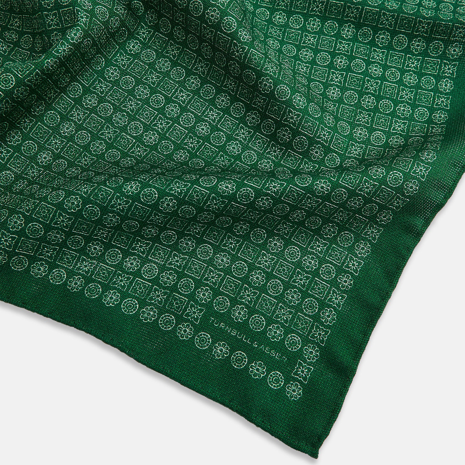 View 3 of product The Rosette Green Pocket Square in Silk by Turnbull & Asser UK features a small geometric medallion pattern and is shown folded to display a contrasting fine black-and-white design on the reverse side.